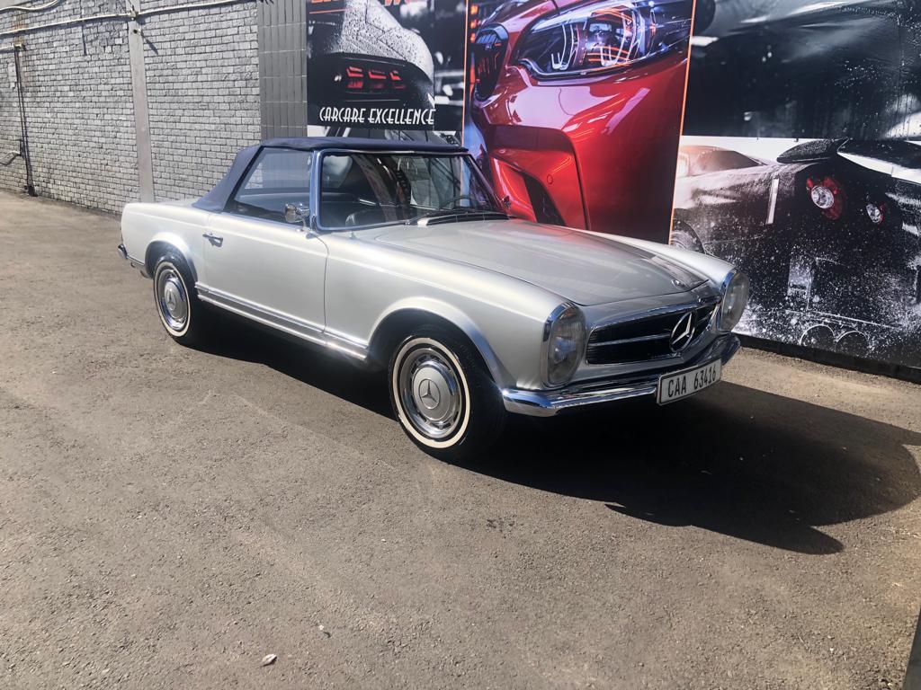 Classic Mercedes convertible parked in front of the Execuwash mural